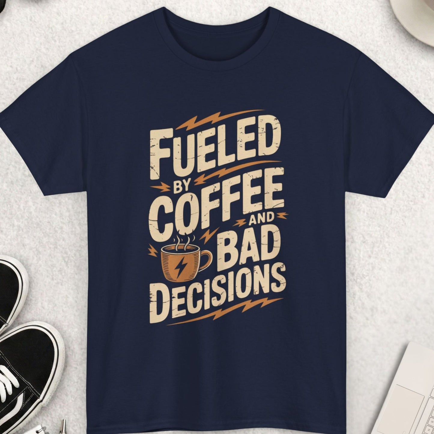 Navy blue t-shirt with 'Fueled by Coffee and Bad Decisions' text on a light gray surface with accessories.