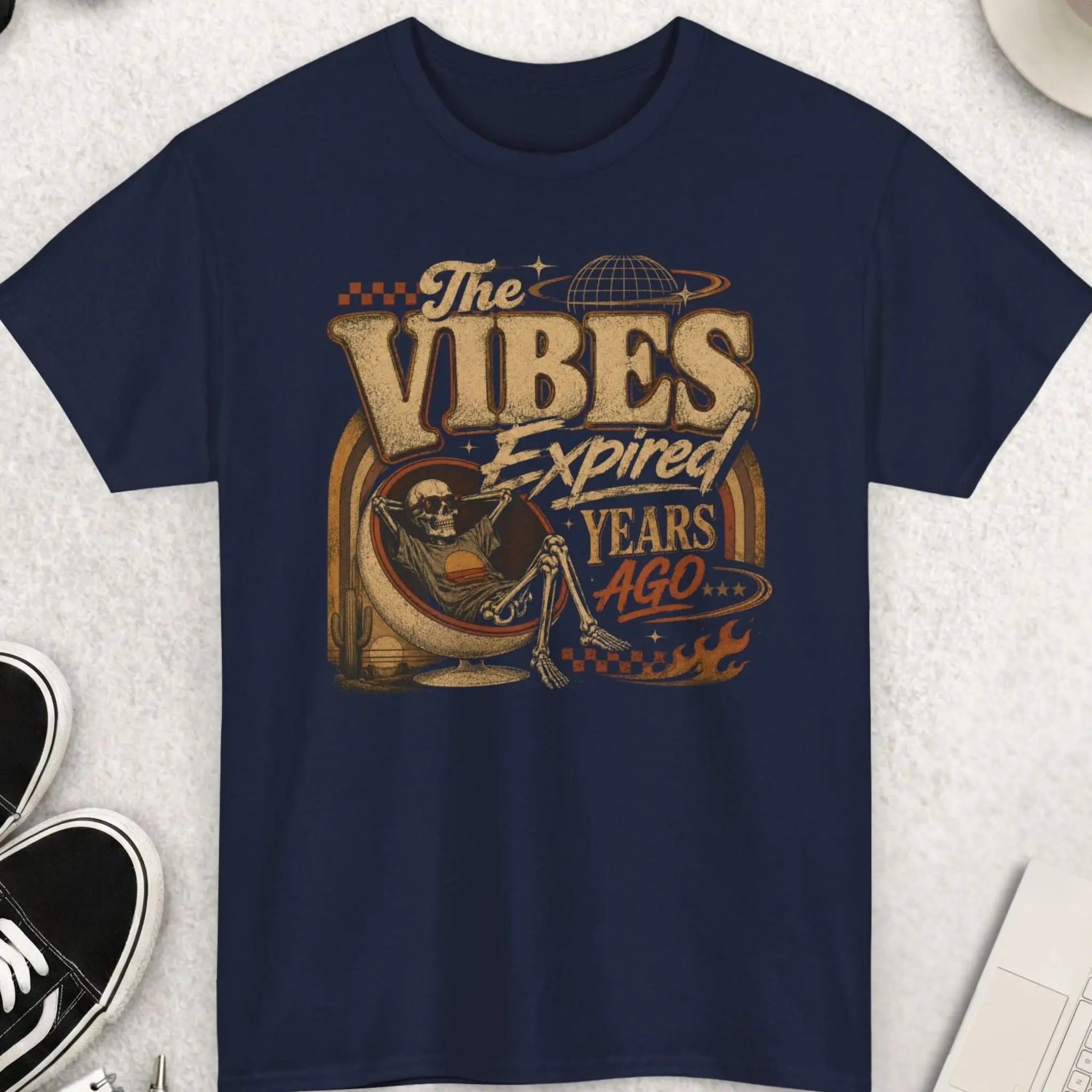 Navy blue vintage streetwear graphic tee featuring distressed typography reading “The Vibes Expired Years Ago” with retro desert artwork and a lounging skeleton in a surreal cosmic setting.