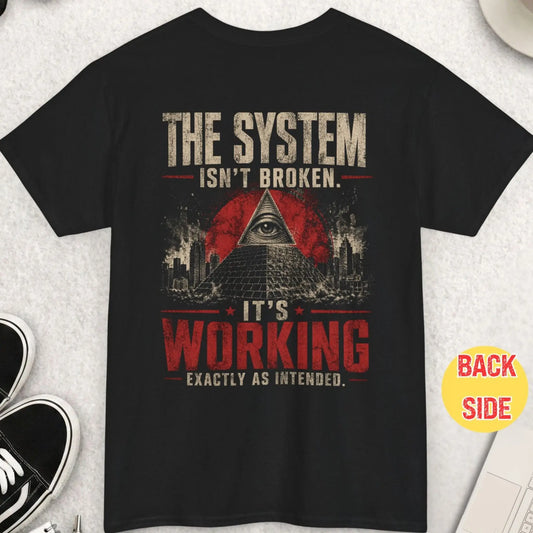 Black t-shirt featuring distressed typography “The system isn’t broken it’s working exactly as intended” with pyramid and all-seeing eye graphic