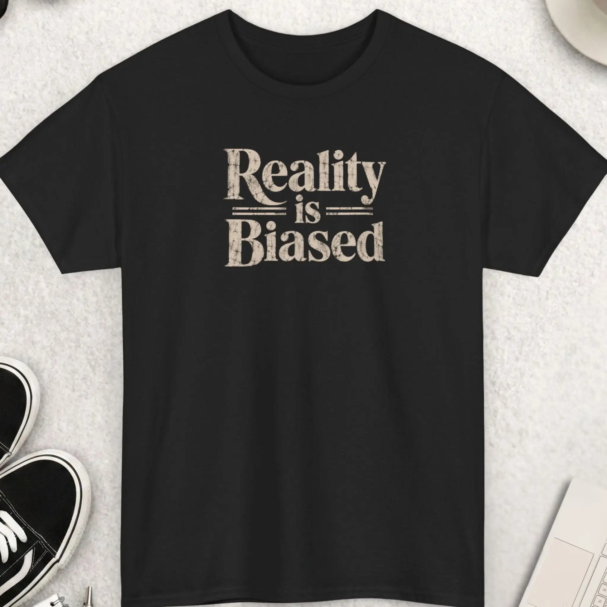 Black t-shirt with distressed bold typography reading “Reality Is Biased” in large vintage-style lettering