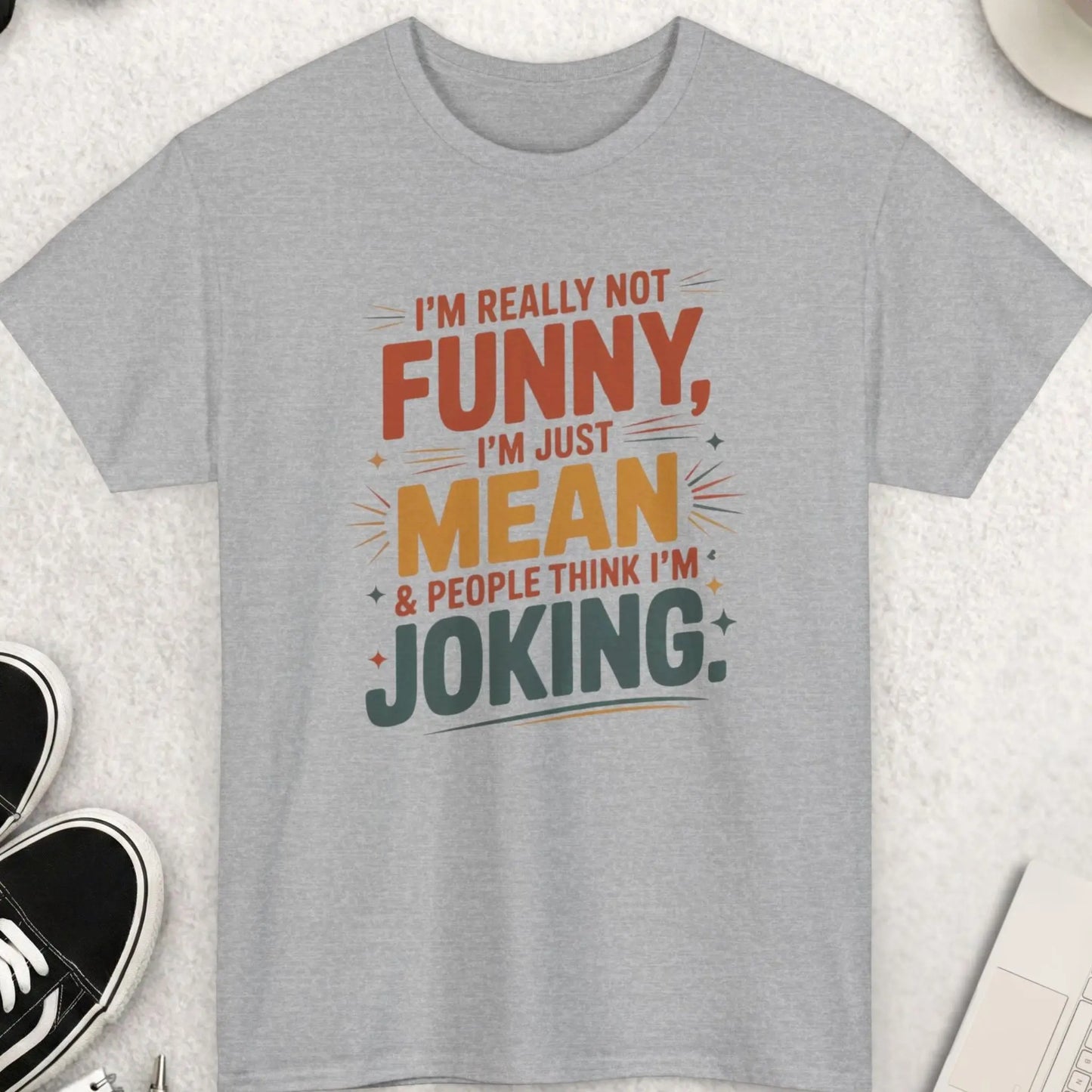 Gray t-shirt with humorous text design on a light surface with accessories.