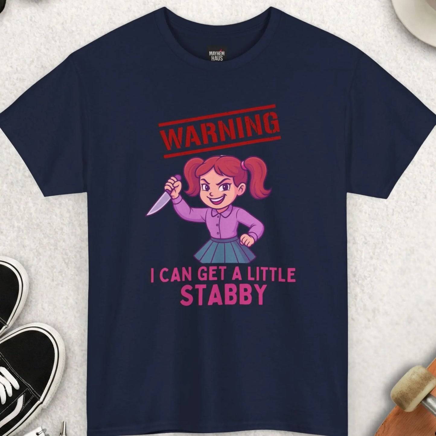 Navy blue t-shirt with cartoon character and text on a light gray surface with accessories.