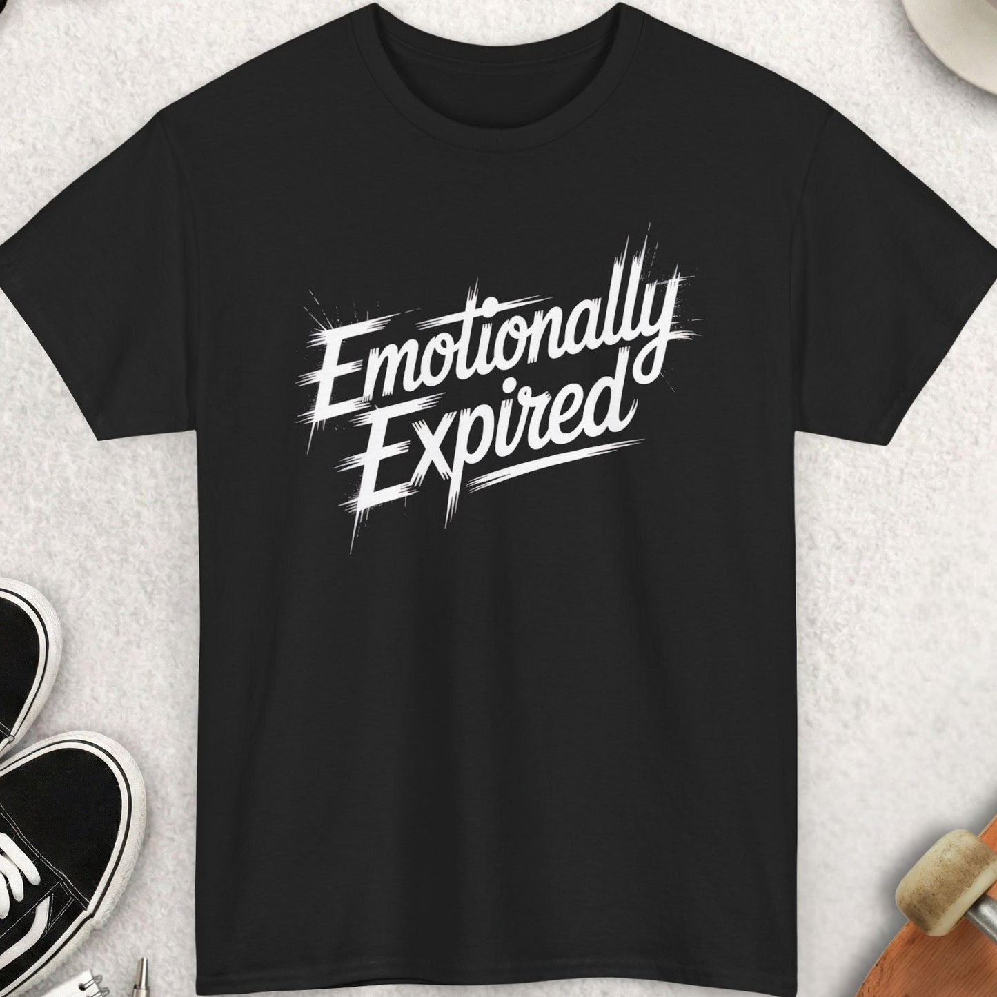 Black t-shirt with 'Emotionally Expired' text on a light gray surface with accessories.