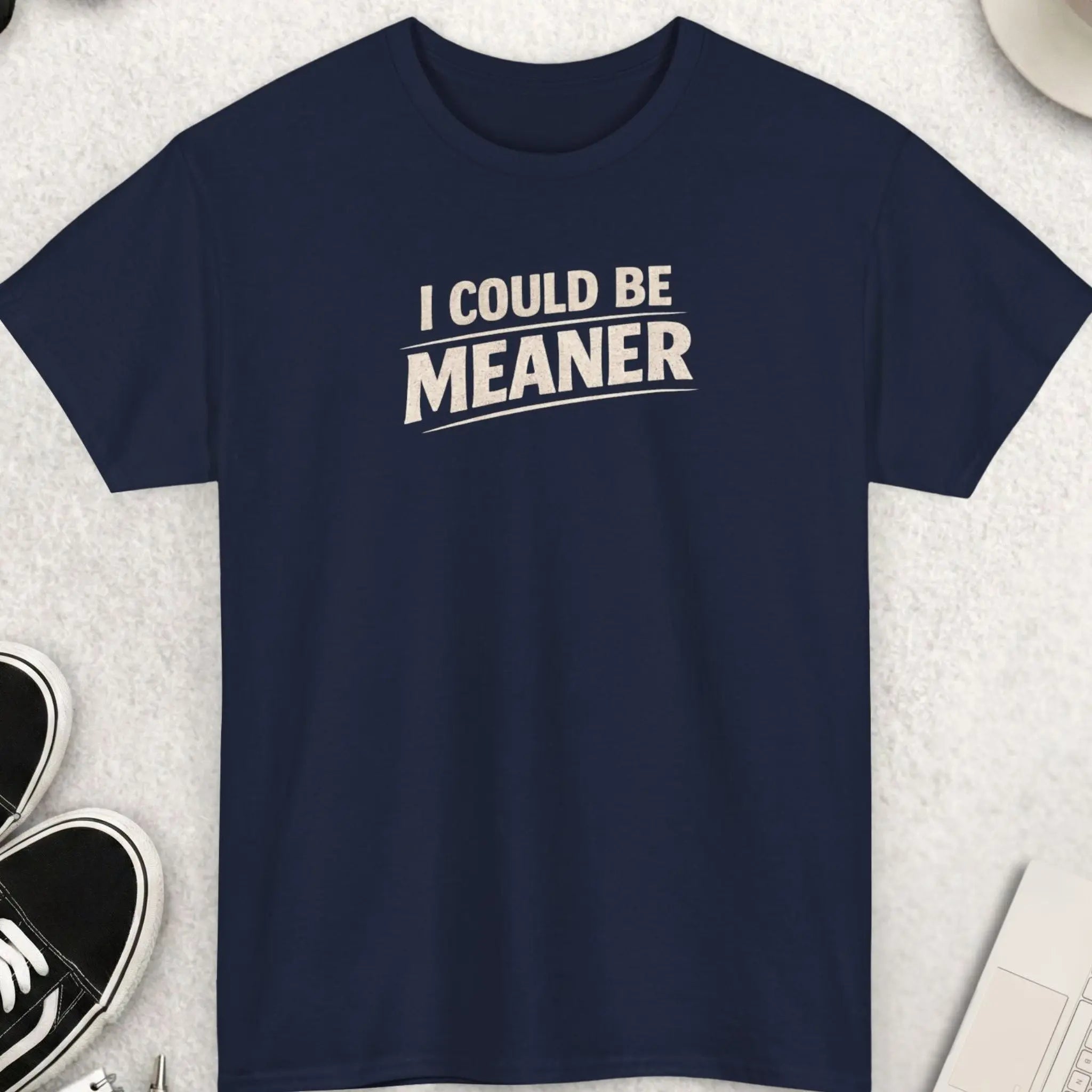 Navy blue t-shirt with 'I Could Be Meaner' text on a light gray surface with accessories.