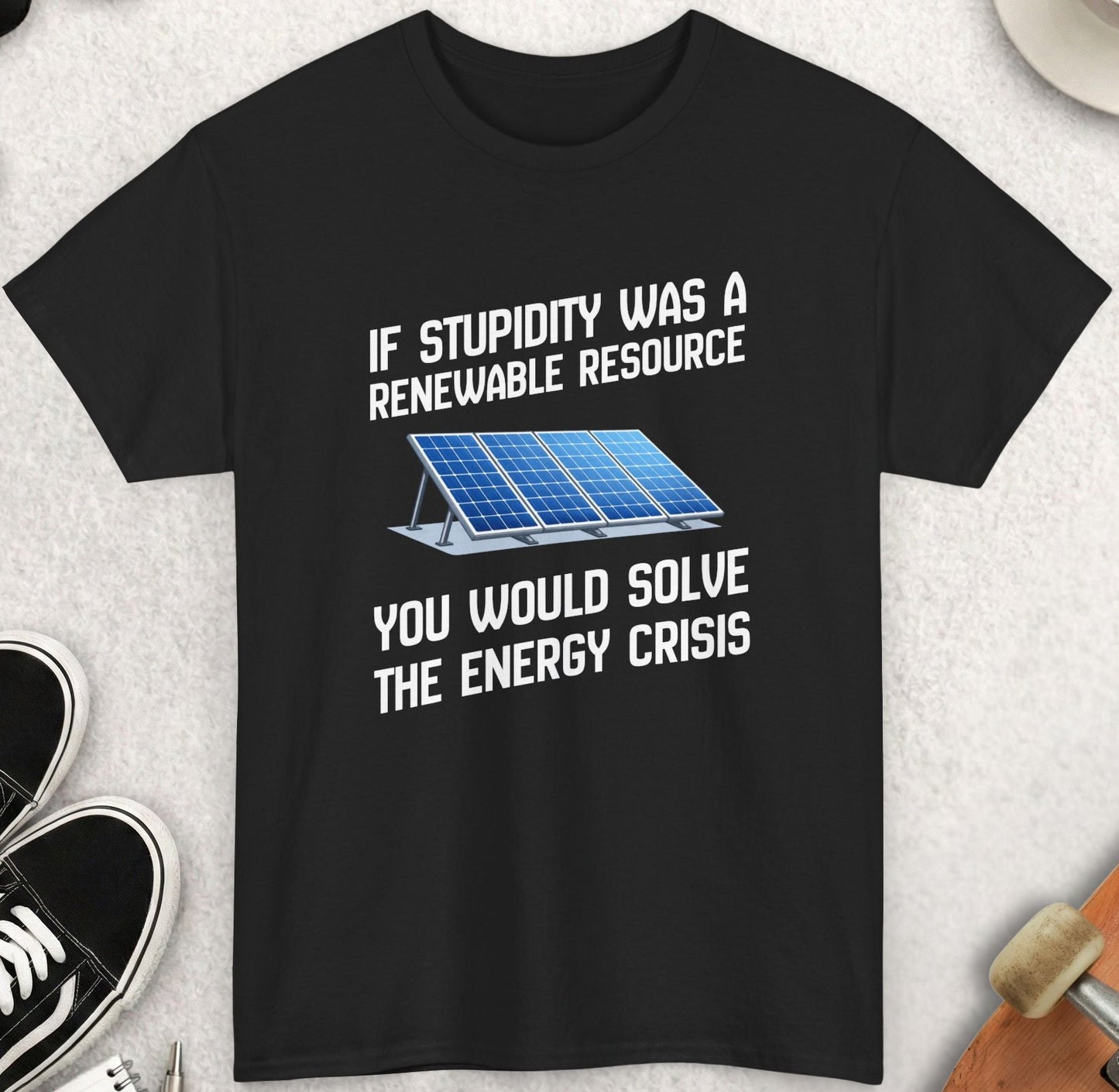 Black t-shirt with humorous text and solar panel graphic on a light gray surface with accessories.