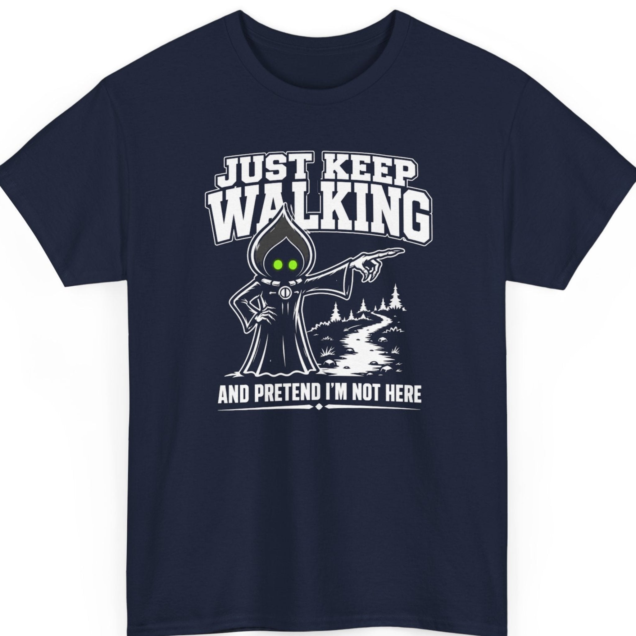Mayhem Haus cryptid t-shirt on a navy blue shirt featuring the Flatwoods Monster pointing down a winding forest path with glowing green eyes and bold white lettering that reads "JUST KEEP WALKING" and "AND PRETEND I'M NOT HERE."