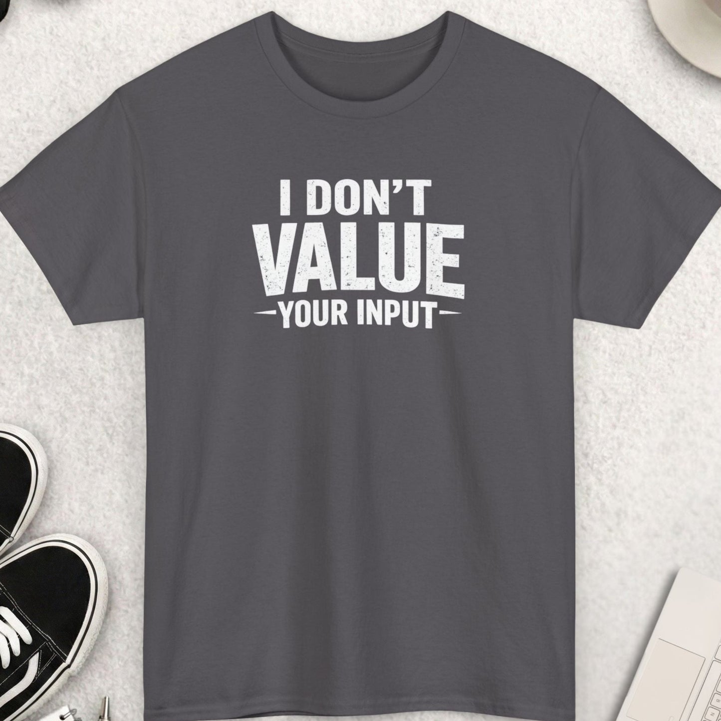 Gray t-shirt with 'I Don't Value Your Input' text on a light gray surface with shoes, sunglasses, and coffee.