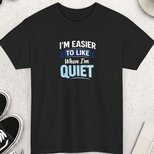 Black t-shirt with humorous text design on a light gray surface with accessories.