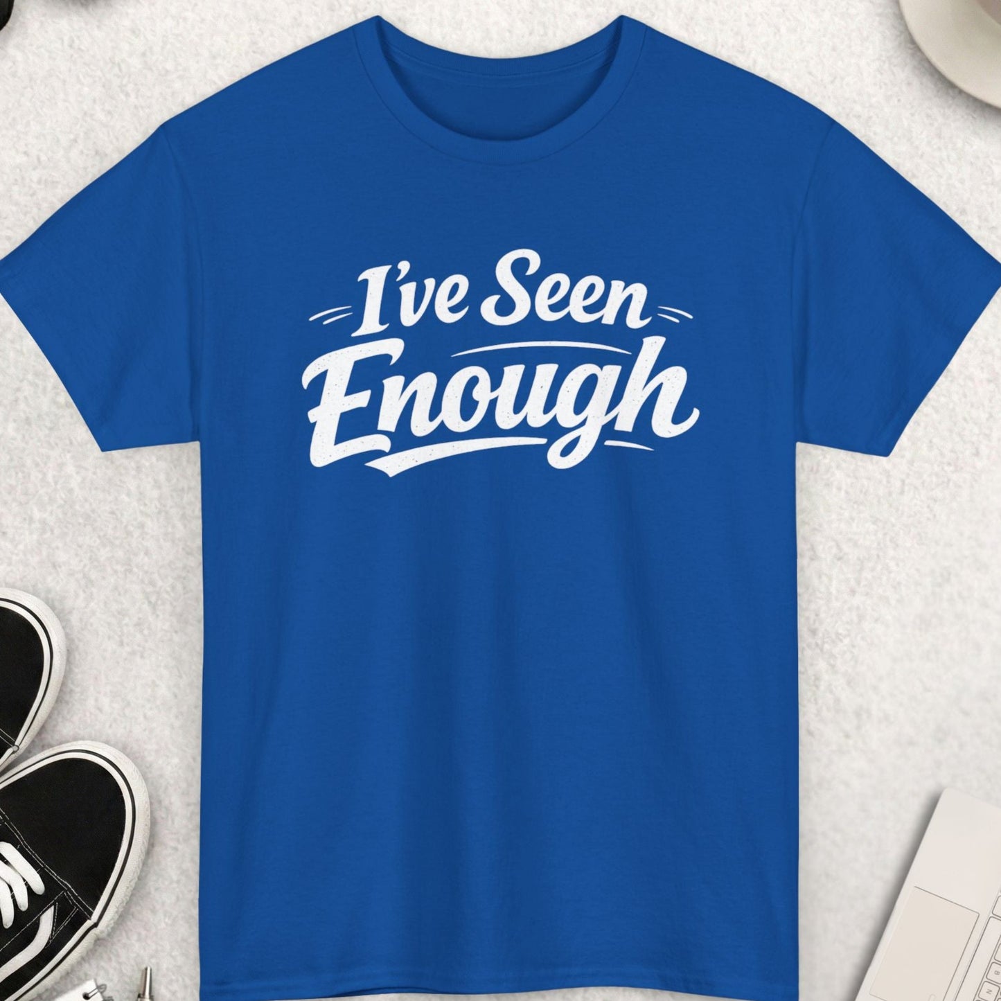 Blue t-shirt with 'I've Seen Enough' text on a light gray surface with accessories.