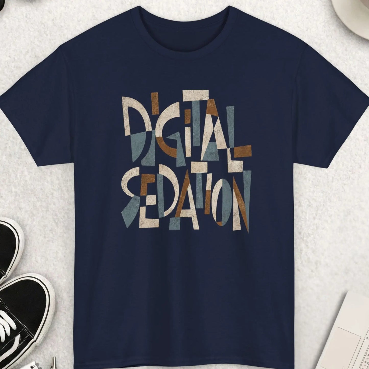 Navy blue graphic t-shirt displaying fragmented Cubist typography with the phrase “Digital Sedation” in muted earth-tone colors and distressed textures.