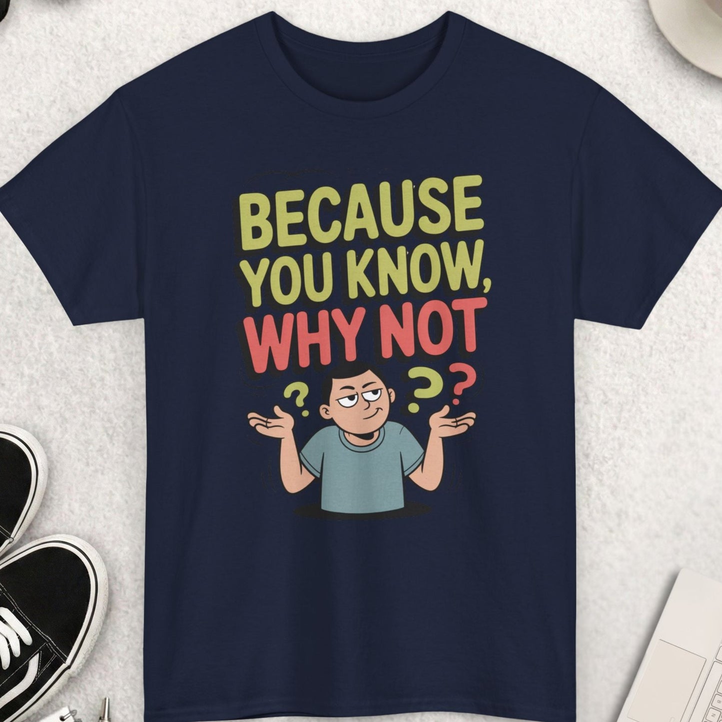 Navy blue t-shirt with humorous design and text on a light gray surface with accessories.