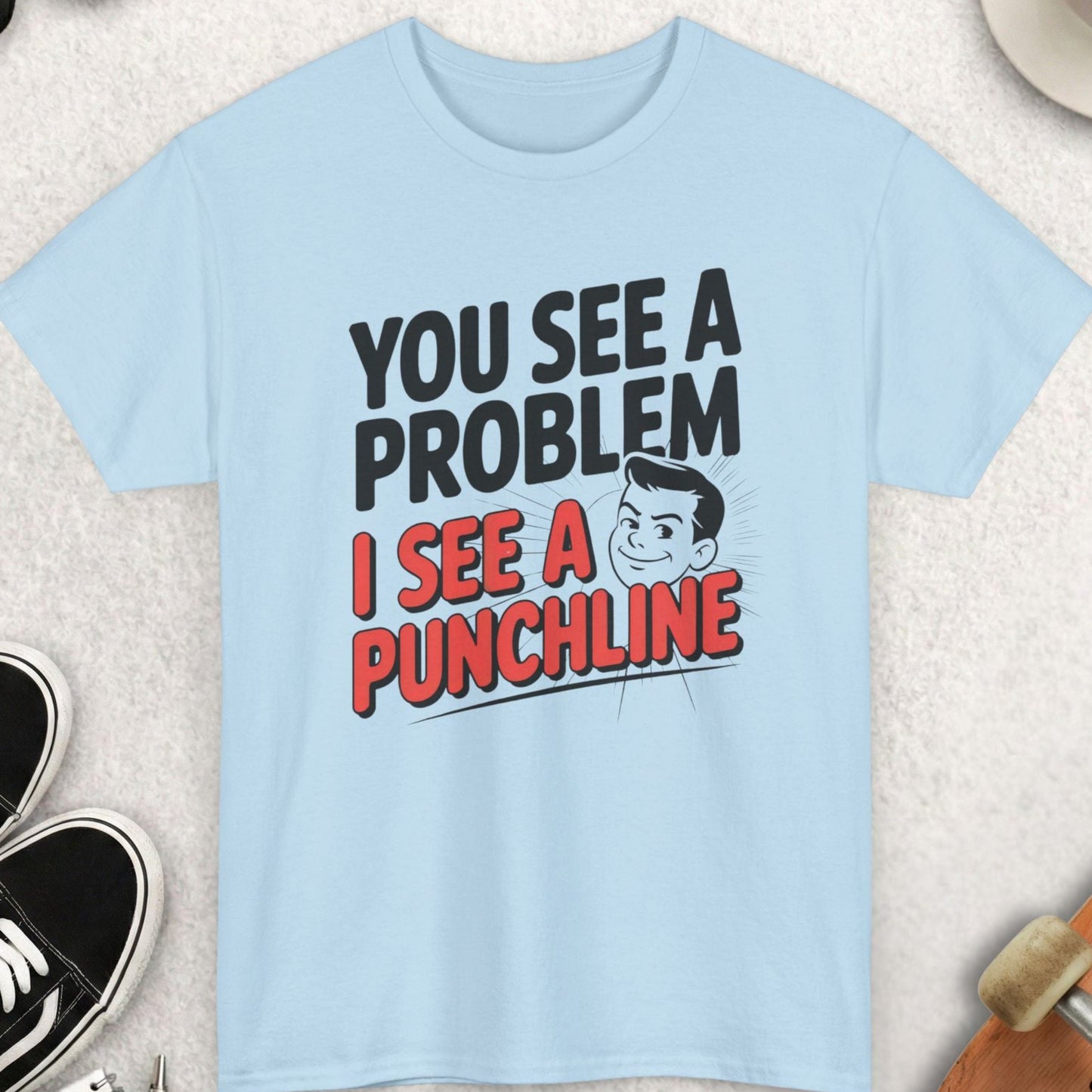 Light blue t-shirt with humorous text design on a textured surface with accessories.