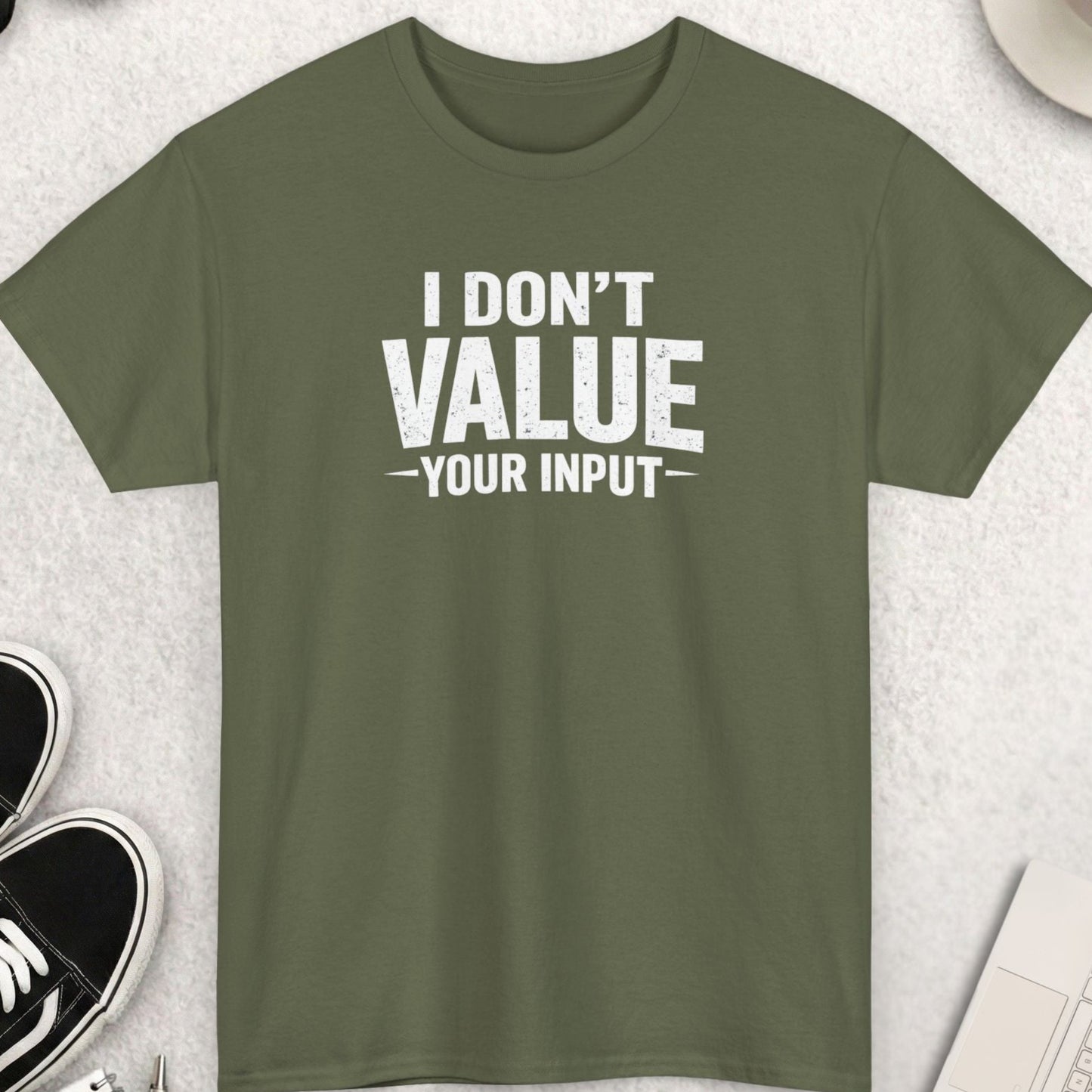 Green t-shirt with 'I Don't Value Your Input' text on a light gray surface with shoes, sunglasses, and coffee.
