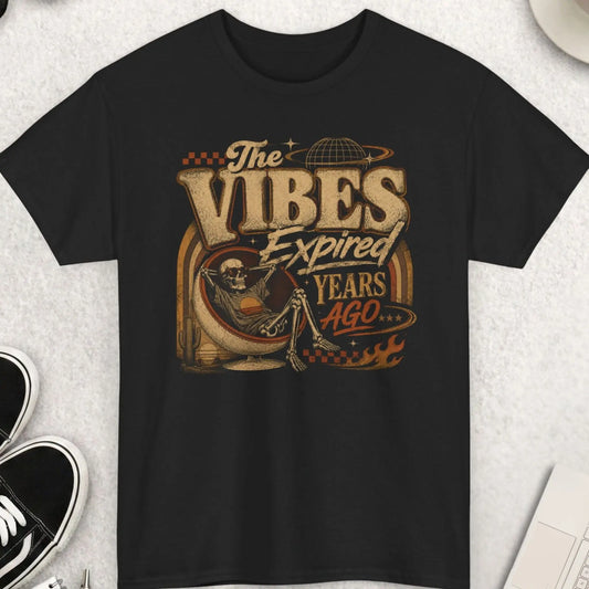 Black retro graphic t-shirt featuring the phrase “The Vibes Expired Years Ago” with distressed vintage typography and artwork of a relaxed skeleton in a retro chair surrounded by desert and cosmic imagery.