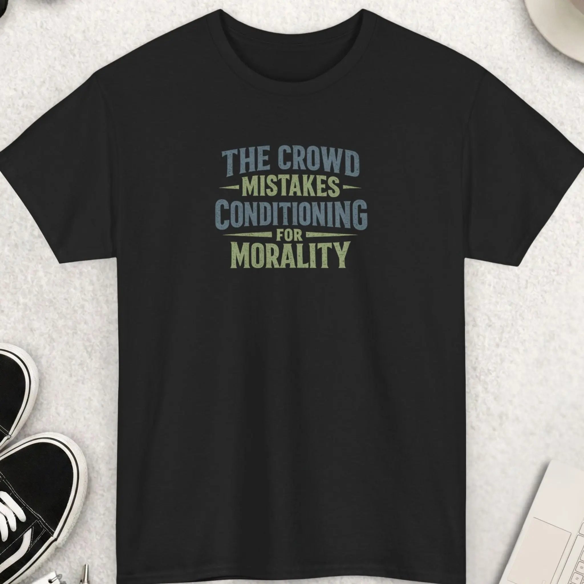 Black t-shirt featuring distressed vintage typography reading “The Crowd Mistakes Conditioning For Morality” in muted earth-tone colors with a bold minimalist layout.