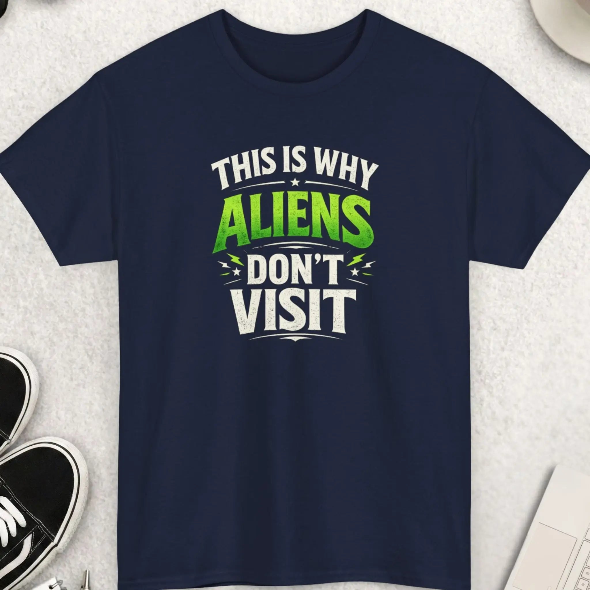 Navy blue t-shirt with humorous text design on a light gray surface with accessories.