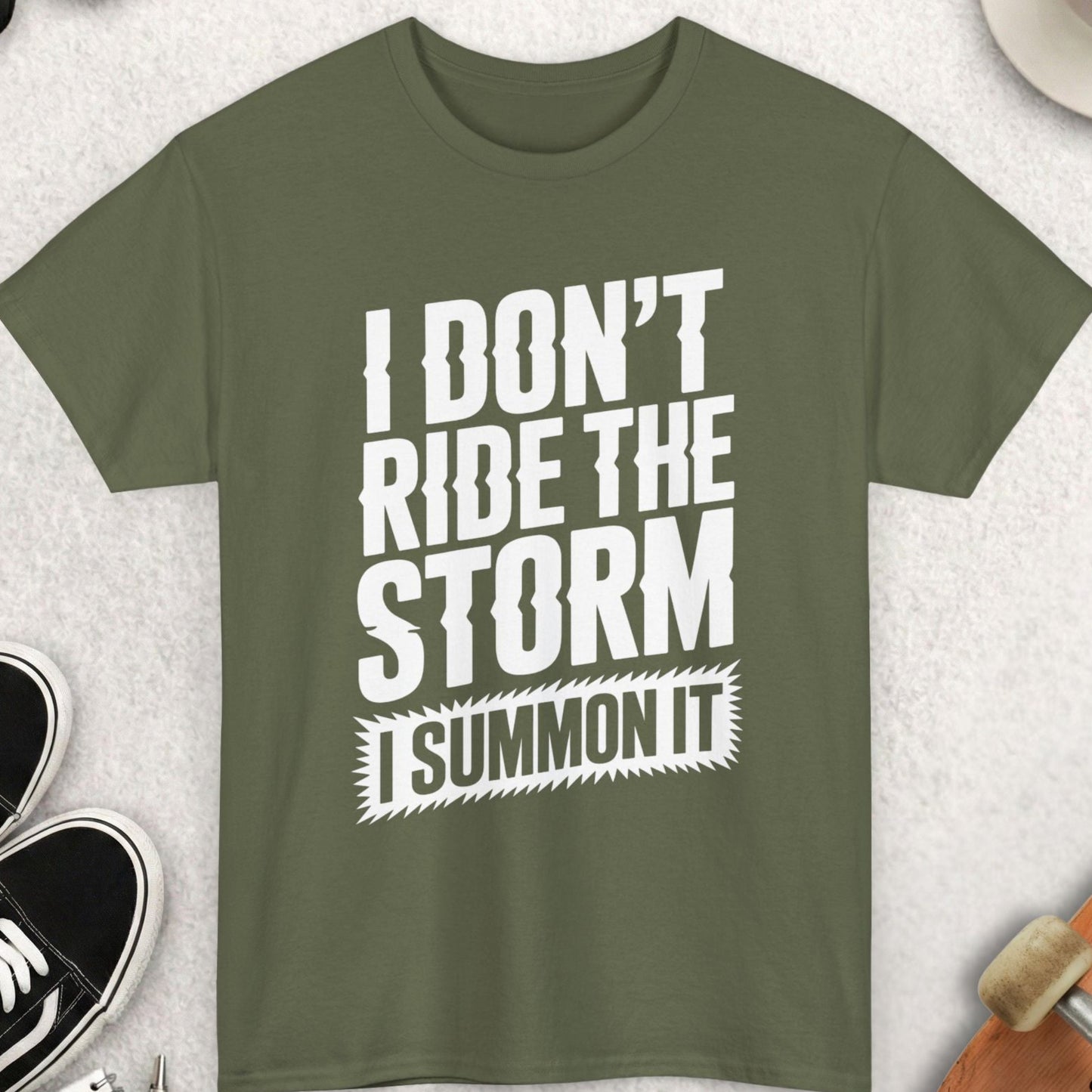 Green t-shirt with 'I don't ride the storm, I summon it' text on a light gray surface with accessories.