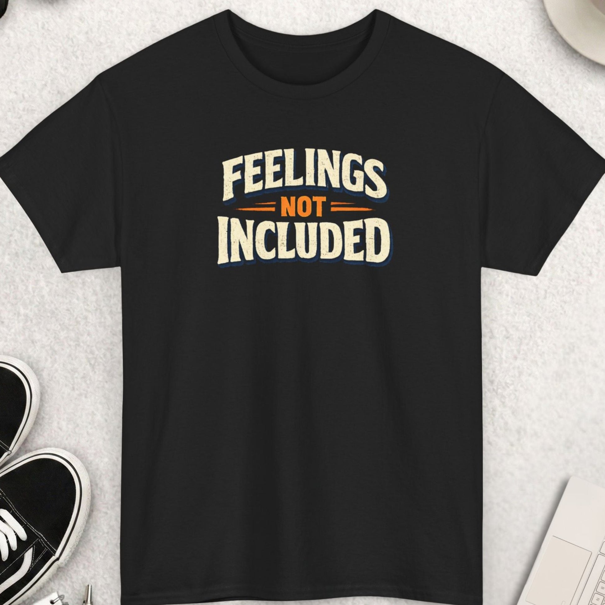 Black t-shirt with 'Feelings Not Included' text on a light gray surface with shoes, coffee, and accessories.