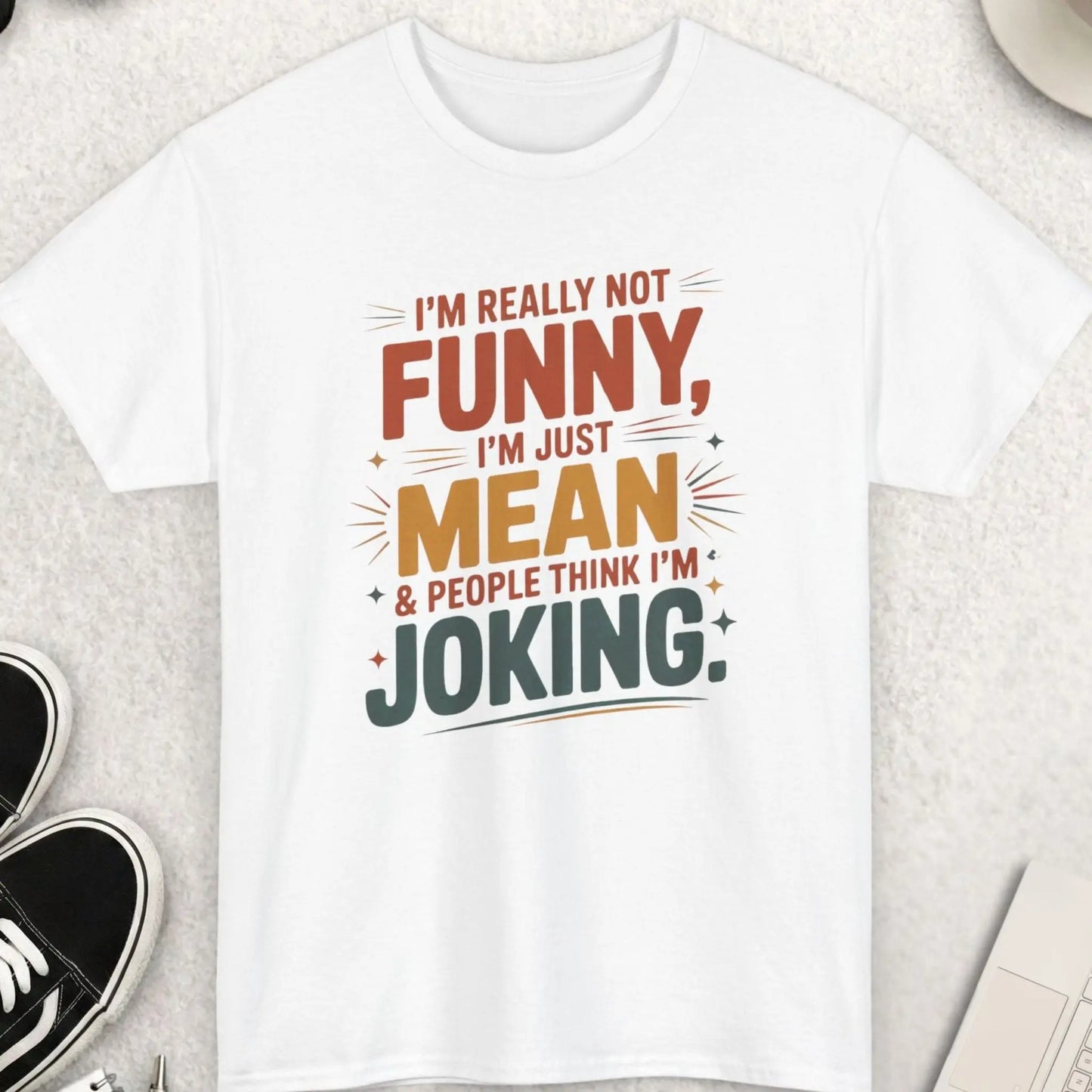 White t-shirt with humorous text design on a light gray surface with accessories.