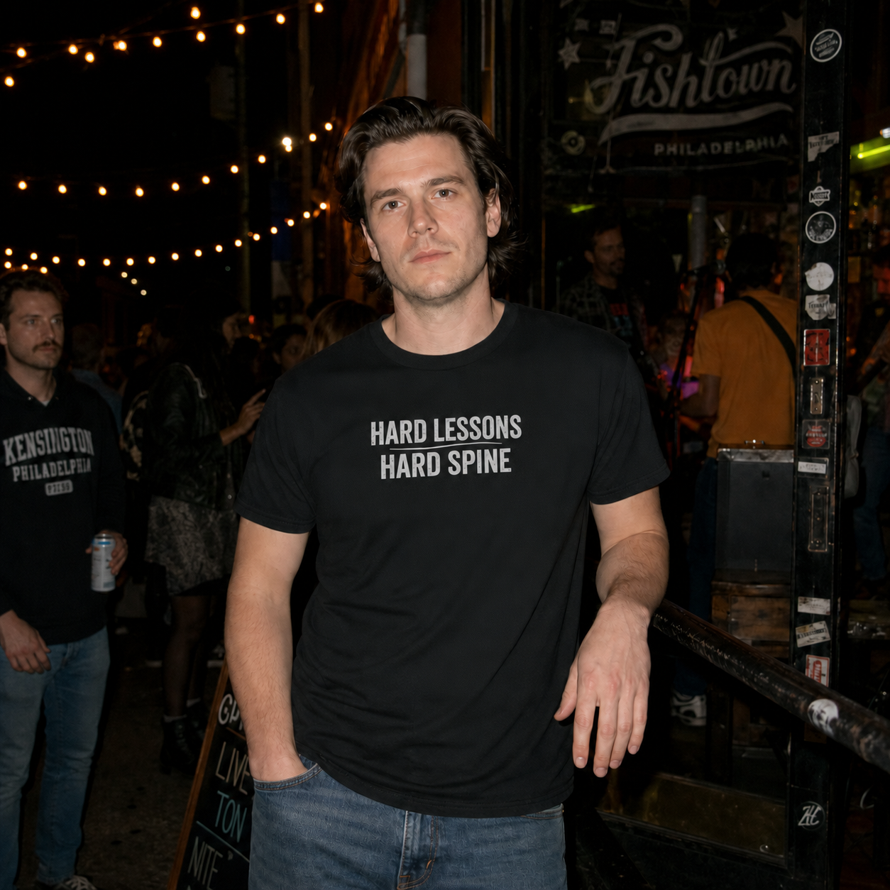 Mayhem Haus Hard Lessons Hard Spine T-Shirt in black, worn by a man at night