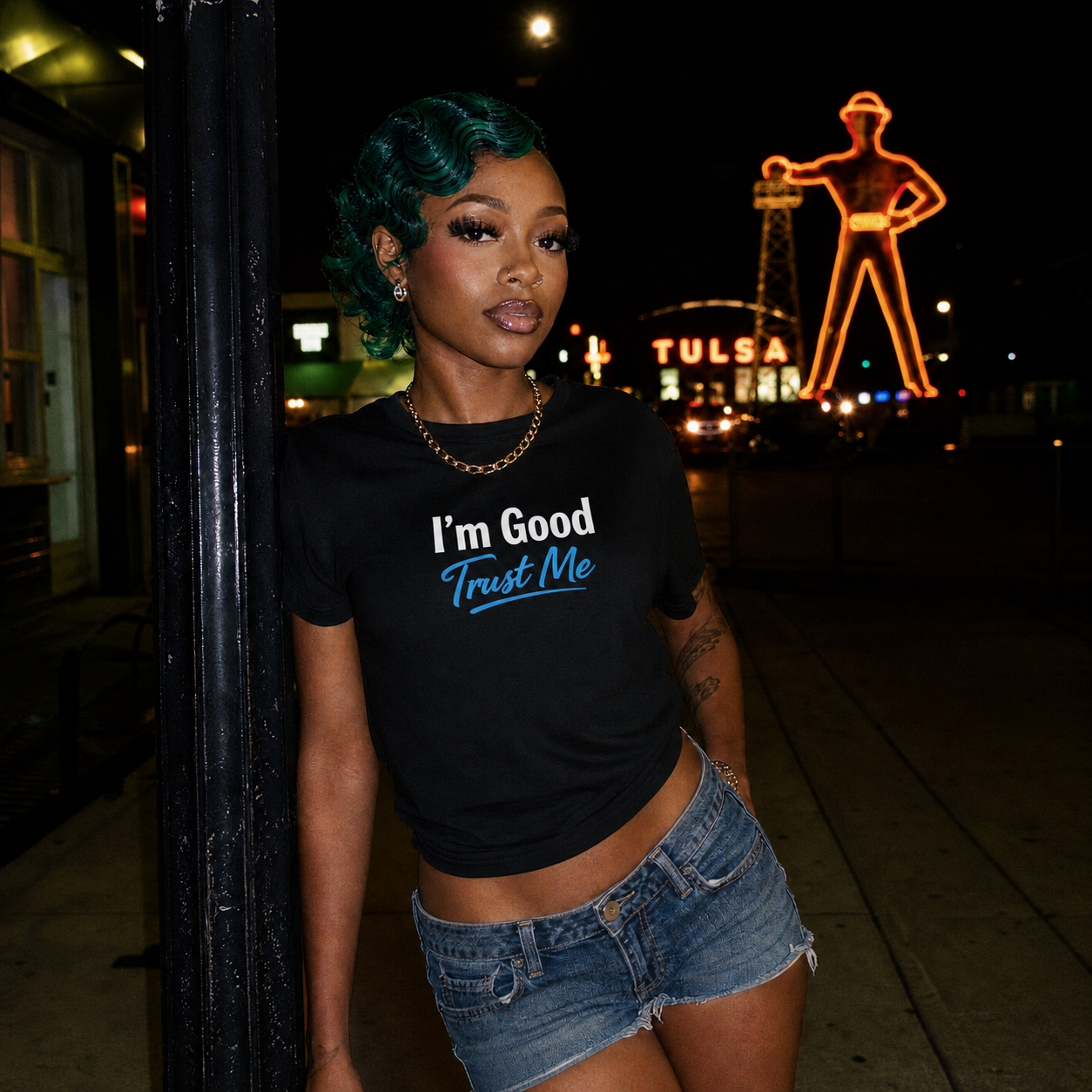 Mayhem Haus I'm Good. Trust Me. T-Shirt on a model with green hair, leaning on a pole at night