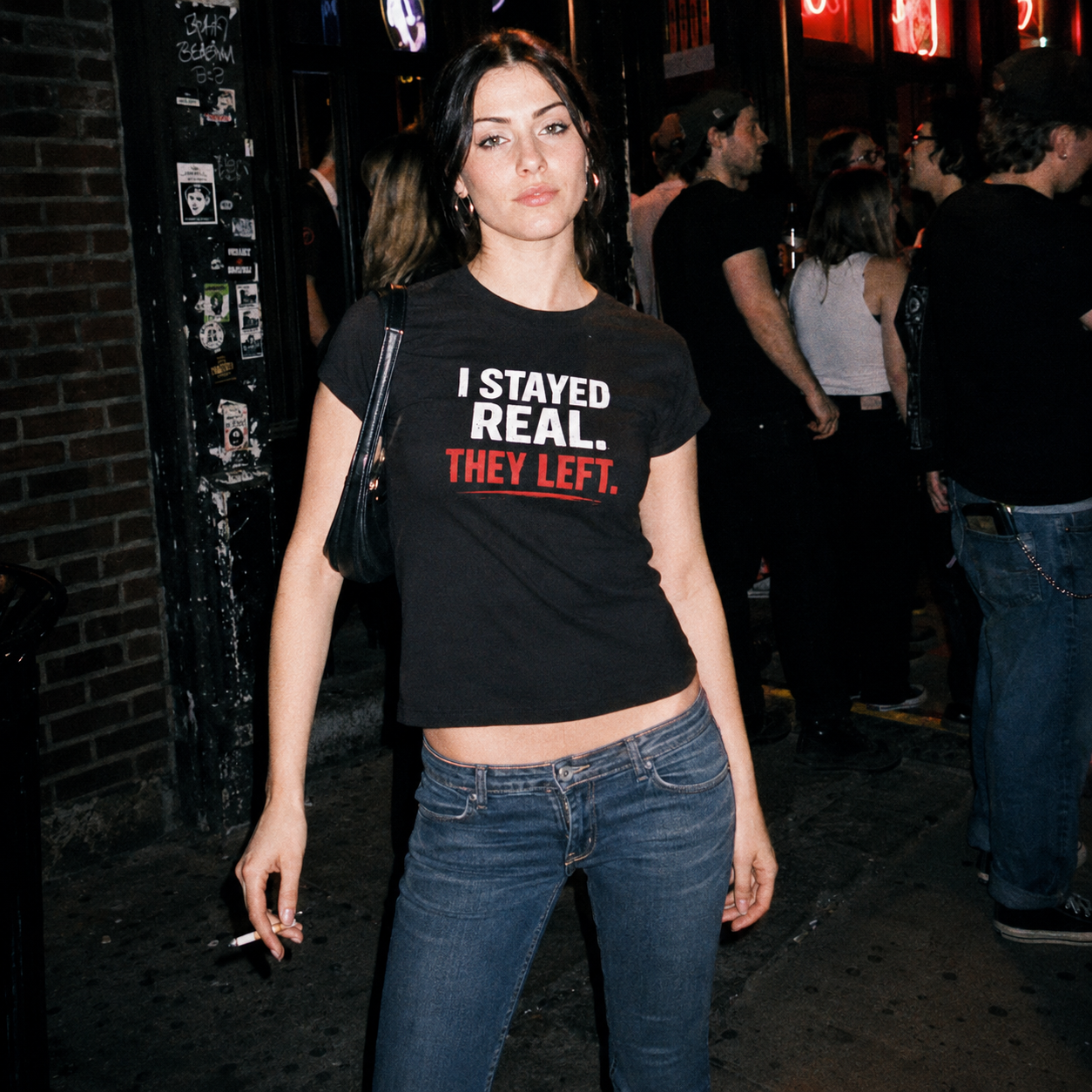 Mayhem Haus I Stayed Real They Left T-Shirt on a woman with dark hair and jeans