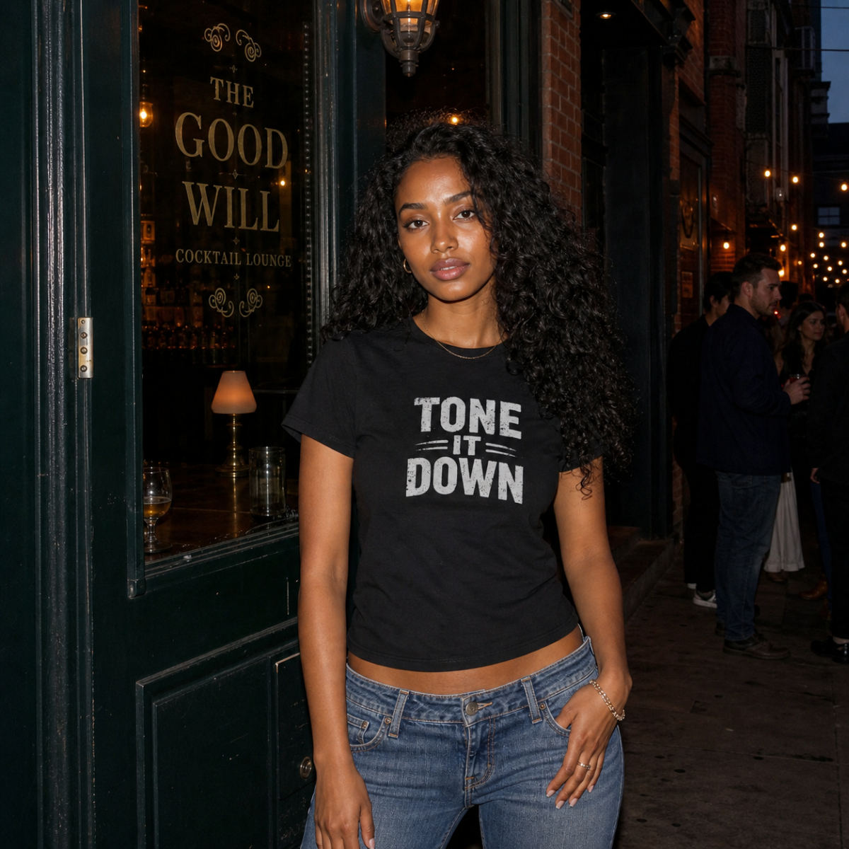 Mayhem Haus Tone It Down T-Shirt in black with white text, worn by a woman with long dark curly hair