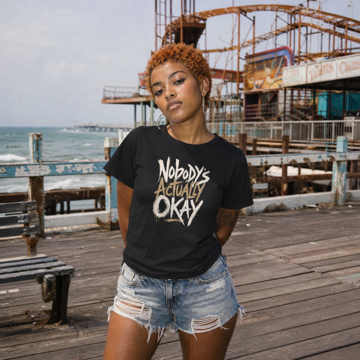 Mayhem Haus Nobody’s Actually Okay T-Shirt on a person on a pier